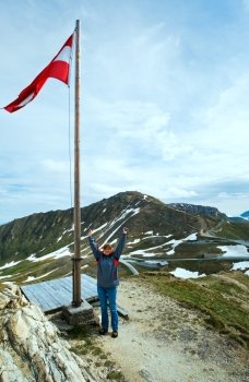 Austrian Flag above Alps mountain (Grossglockner High Alpine Road) and woman - tourist near