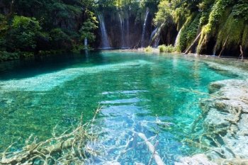 Beautiful lake with clear sea-green water and waterfall behind (Plitvice Lakes National Park, Croatia)