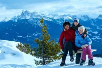 Family (mother with  two children) take a walk on winter mountain slope (view from Rittner Horn on Puez Geislergruppe on left, Italy)