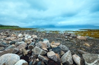Norwegian Sea cloudy view with stony coast.