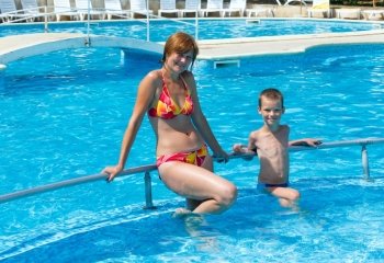 Mother with his son in the summer outdoor pool.