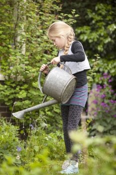 young girl in lush garden watering the plants