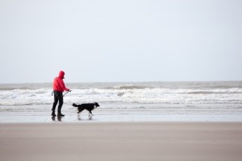 man and dog on windy beach