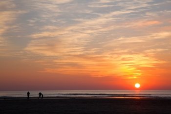 people on beach in holland at sundown