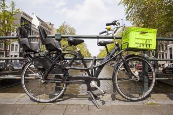 black transport bicycle for children and groceries on bridge over canal in amsterdam