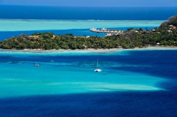 Travel and Stock Photography. View over beautiful turquoise lagoon of bungalows, island and boats. Bora Bora Island, Tahiti, Society Islands, French Polynesia.