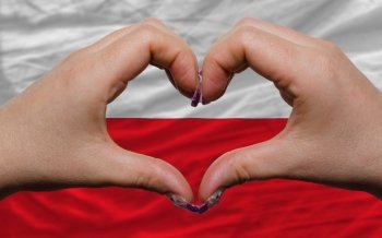 Gesture made by hands showing symbol of heart and love over national poland flag