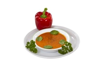 Fresh basil tomato soup in bowl with plate on white background