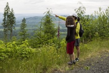 Mother and daughter hiking on mountain trail during summer 