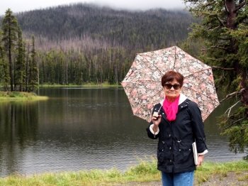 Image of senior women, holding umbrella, while near lake in Yellowstone National Park