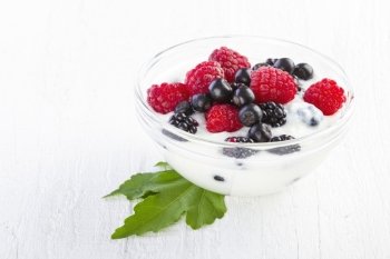 yogurt with forest berries in bowl white wooden background