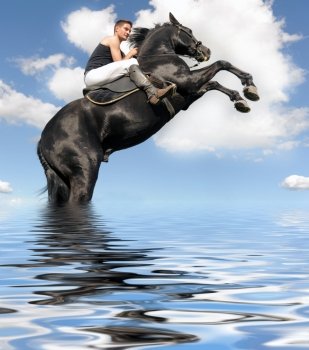 young man and her beautiful black stallion rearing up in the water