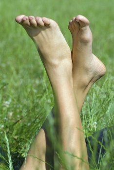 person resting her feet in the fresh spring vegetation under sunshine