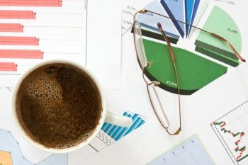 close- up of coffee cup, glasses and business charts