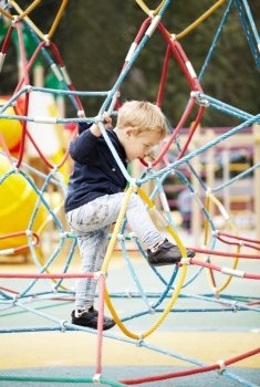 Happy little boy climbing on playground equipment as he enjoys the adventure and exercise