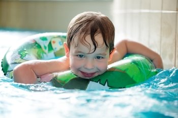Young boy in inflatable tube swimming with a big smile on his face