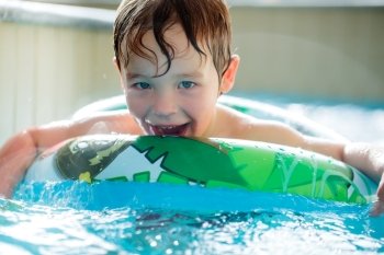 Cute boy in inflatable ring having fun in the swimming pool