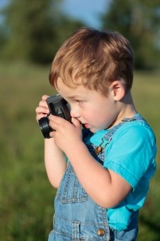Little boy with camera taking pictures outdoor