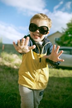 Happy little boy having fun in big sunglasses outdoor
