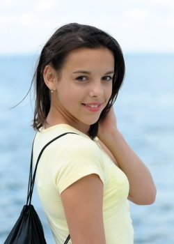 Portrait of beautiful smiling girl with backpack on sea background. Focus on the girl
