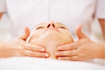 Close-up shot of woman on seance of facial massage with accent on chin
