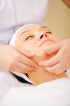 Close-up shot of massage therapist doing a facial massage at beauty treatment salon