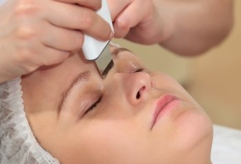 Close-up shot of a woman at beauty spa getting facial treatment with ultrasonic facial cleaning