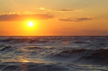 Golden sunset over wavy sea. Rough water sparkling in the evening sunlight