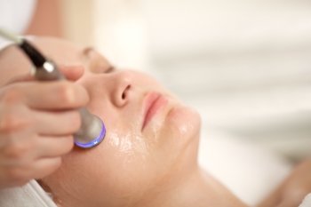 Close-up shot of woman getting professional facial treatment with special equipment. Cosmetician doing lifting procedure