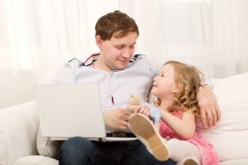Little girl wants to play with dad. Father working with computer, but he giving attention to his daughter