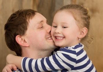 Happy young father kissing little daughter. Smiling girl embracing beloved dad. Happy father kissing little daughter