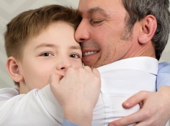 Close-up shot of a son giving father a hug. Boy devoted to his beloved dad