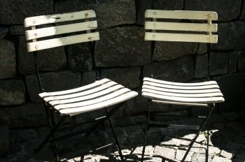 Two vintage folding chairs on stone background