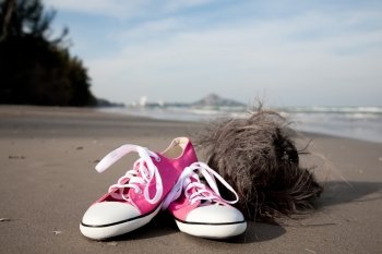 Pink sports boots and old coconut on the beach