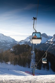 Ski lift cabins against clear blue sky. Italian Alps Resort.
