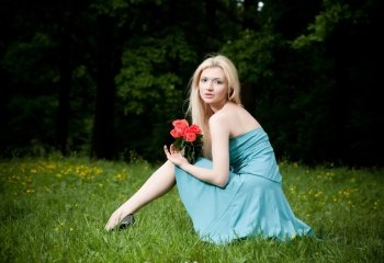 Pretty Woman With Roses Sitting On The Meadow