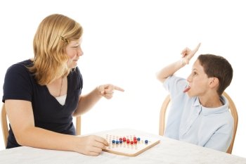 Little brother driving his teenage sister crazy while they play a board game.  Isolated on white.