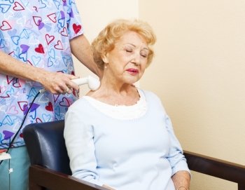 Senior chiropractic patient gets ultrasound therapy for her neck pain.  