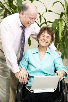 Disabled businesswoman and her boss laughing together as they surf the internet.  