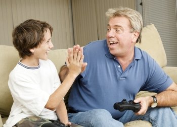 Uncle giving his nephew a high five as they play video games.  Could also be father and son.  