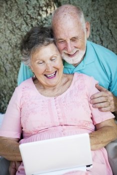 Senior couple stays in touch with the grandchildren using a small netbook laptop computer.  