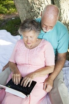Senior couple using a tiny wireless netbook computer outdoors.  