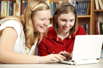 Two teenage girls using a netbook computer in the school library.  
