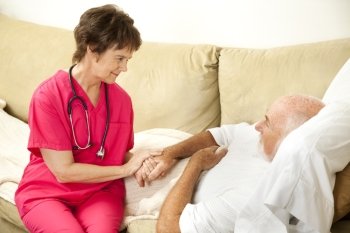 Compassionate home health nurse holds an elderly patient’s hand.  