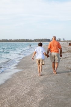 Rear view of senior couple walking on the beach.