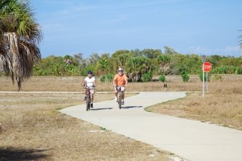 Active senior couple bicycling through the park.  