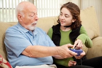 Teen girl teaching her grandfather how to play video games.  