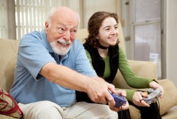 Senior man playing a video game with his teenage granddaughter.  