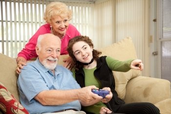 Senior couple playing video games with their teenage granddaughter.