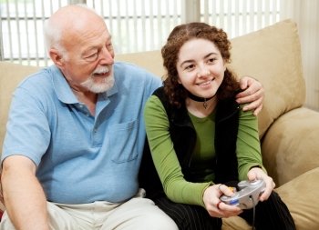 Grandfather watching teen granddaughter play video games.  